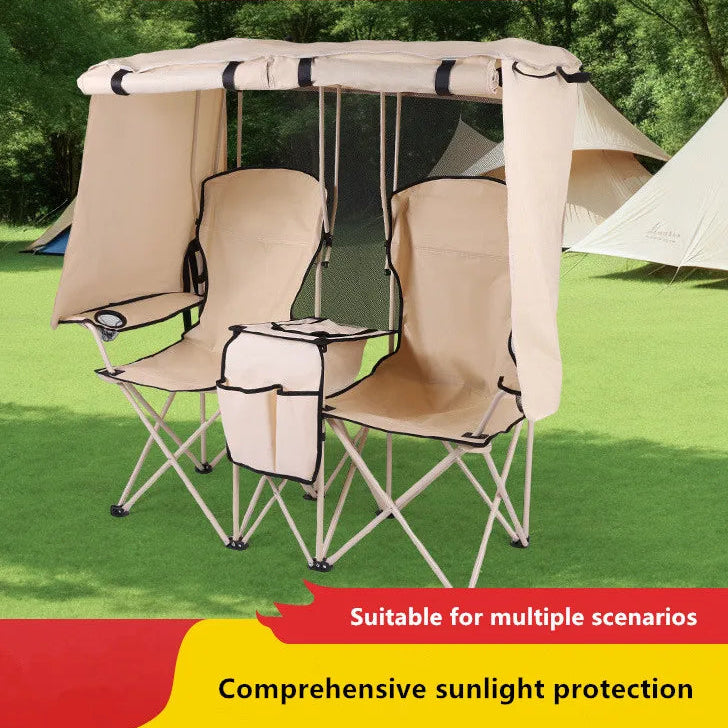 Double camping chair with canopy on grass with trees in the background